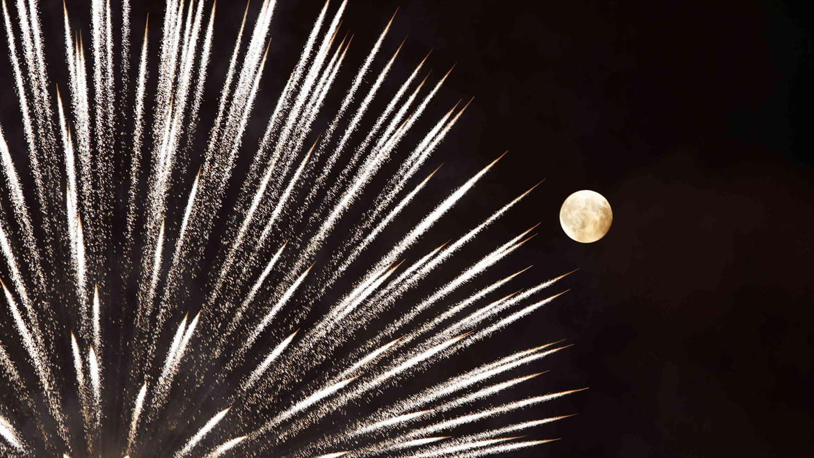 Fireworks explode in front of the supermoon outside the town of Mosta