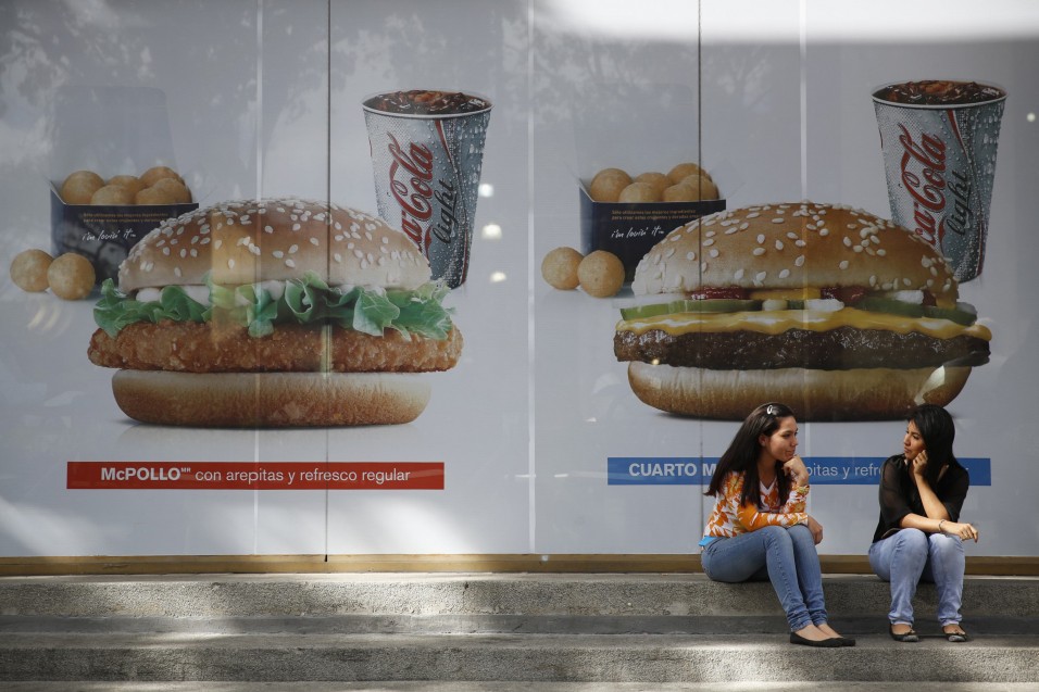 Women chat in front of a McDonald's restaurant in Caracas