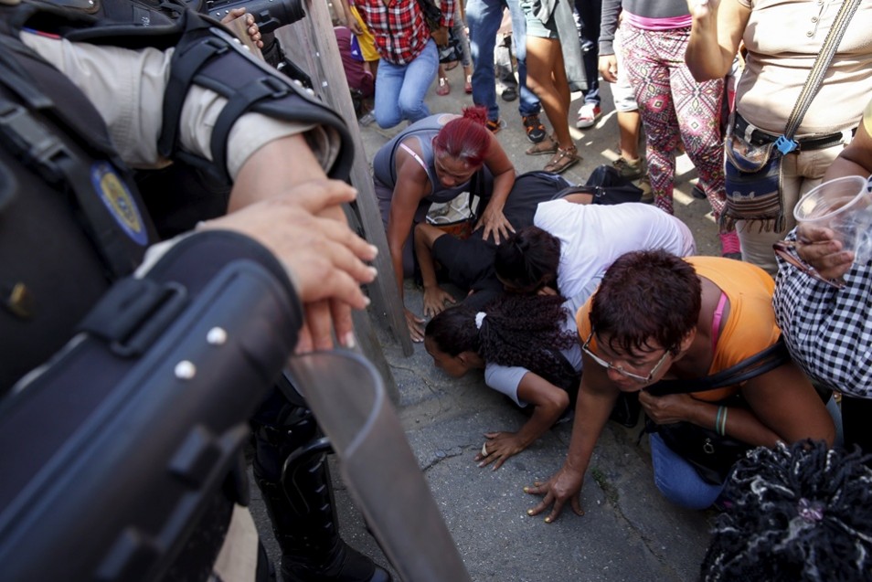 Relatives of inmates try to look to inside the National Bolivarian Police prison as police officers stand guard, during a prison riot in Caracas